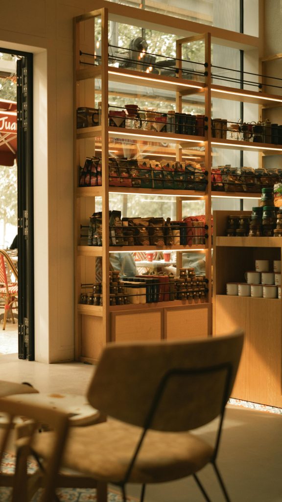 Ambiance chaleureuse de café avec des étagères en bois présentant divers produits dans un cadre moderne.